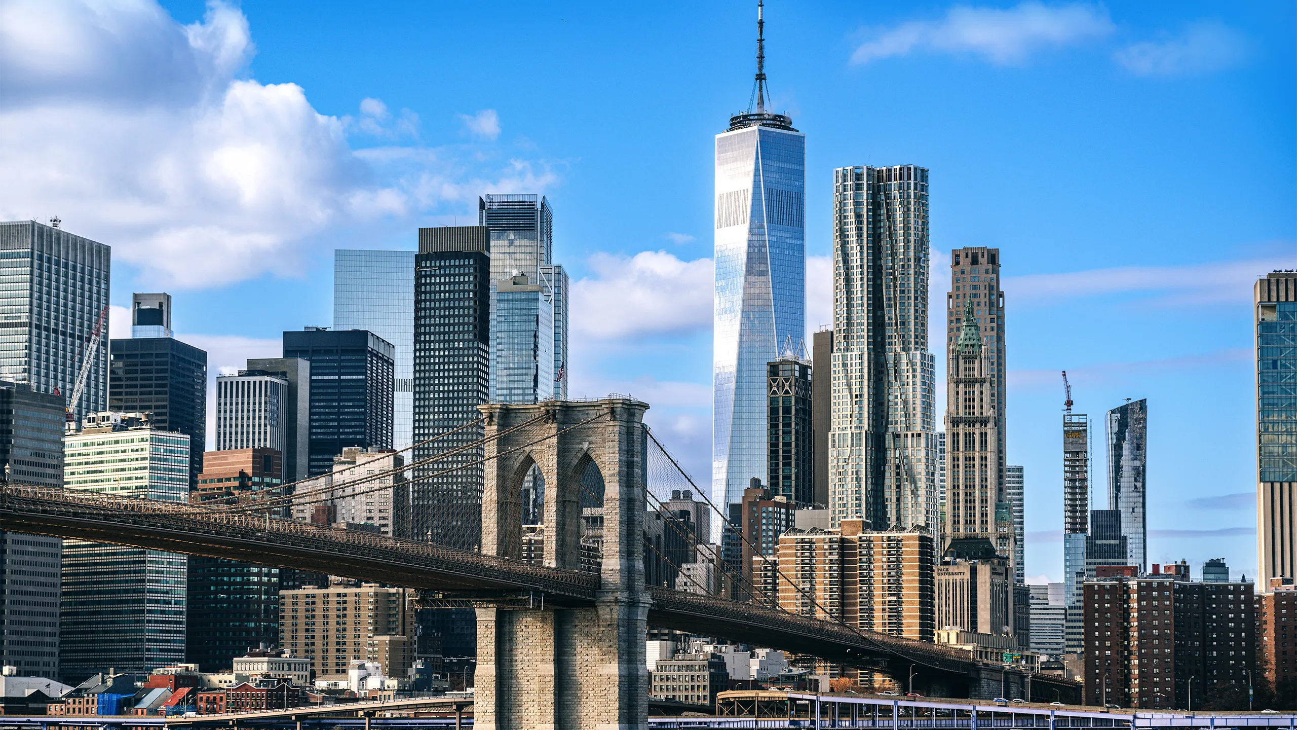 Iconic view featuring the Brooklyn Bridge against the modern New York City skyline on a clear day, showcasing the city's architectural beauty and urban energy.