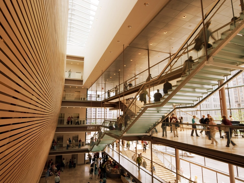 Interior of office building with wood panelling, glass stairs and workers