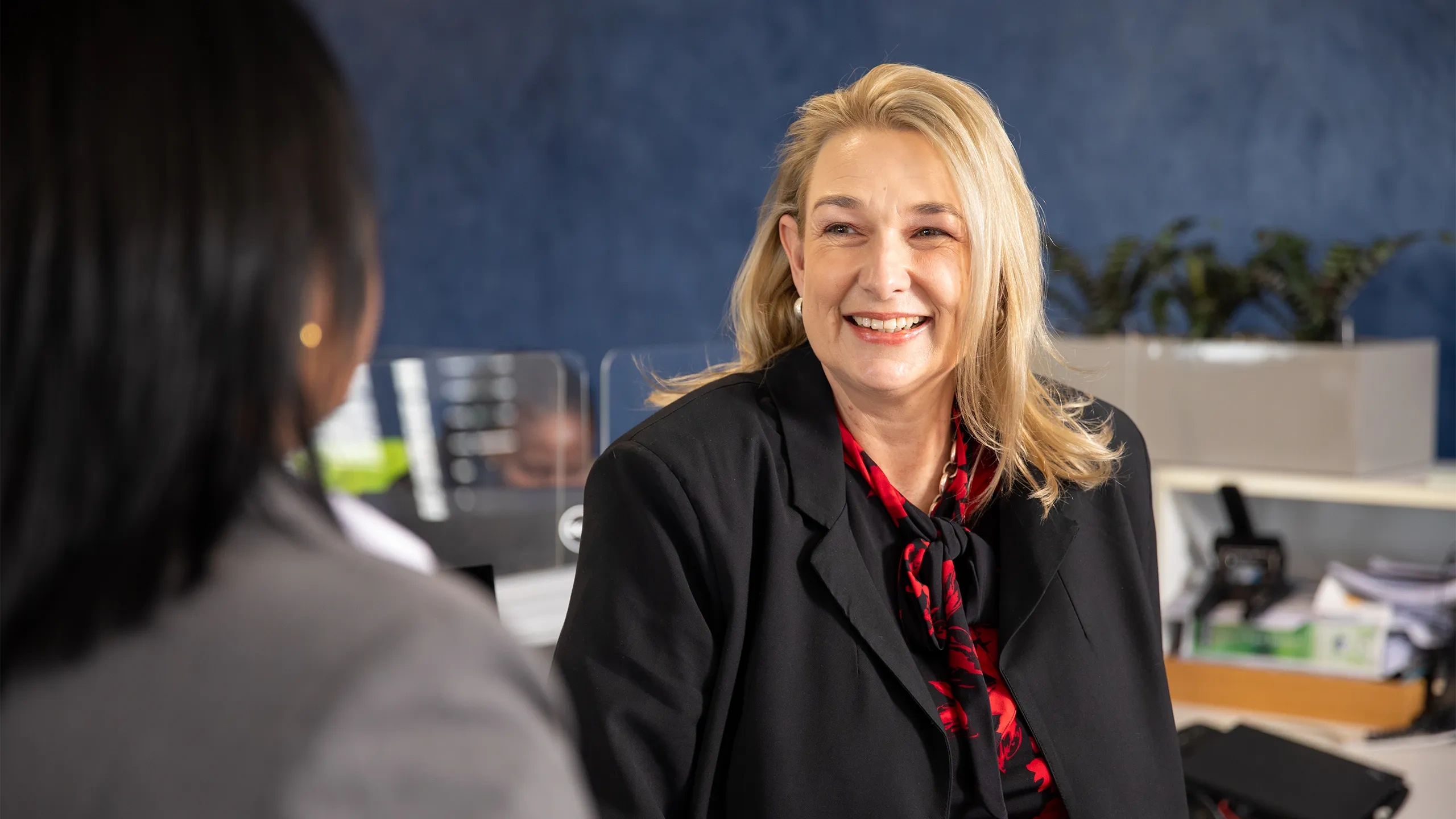 Female employee with blonde hair smiling in office space.