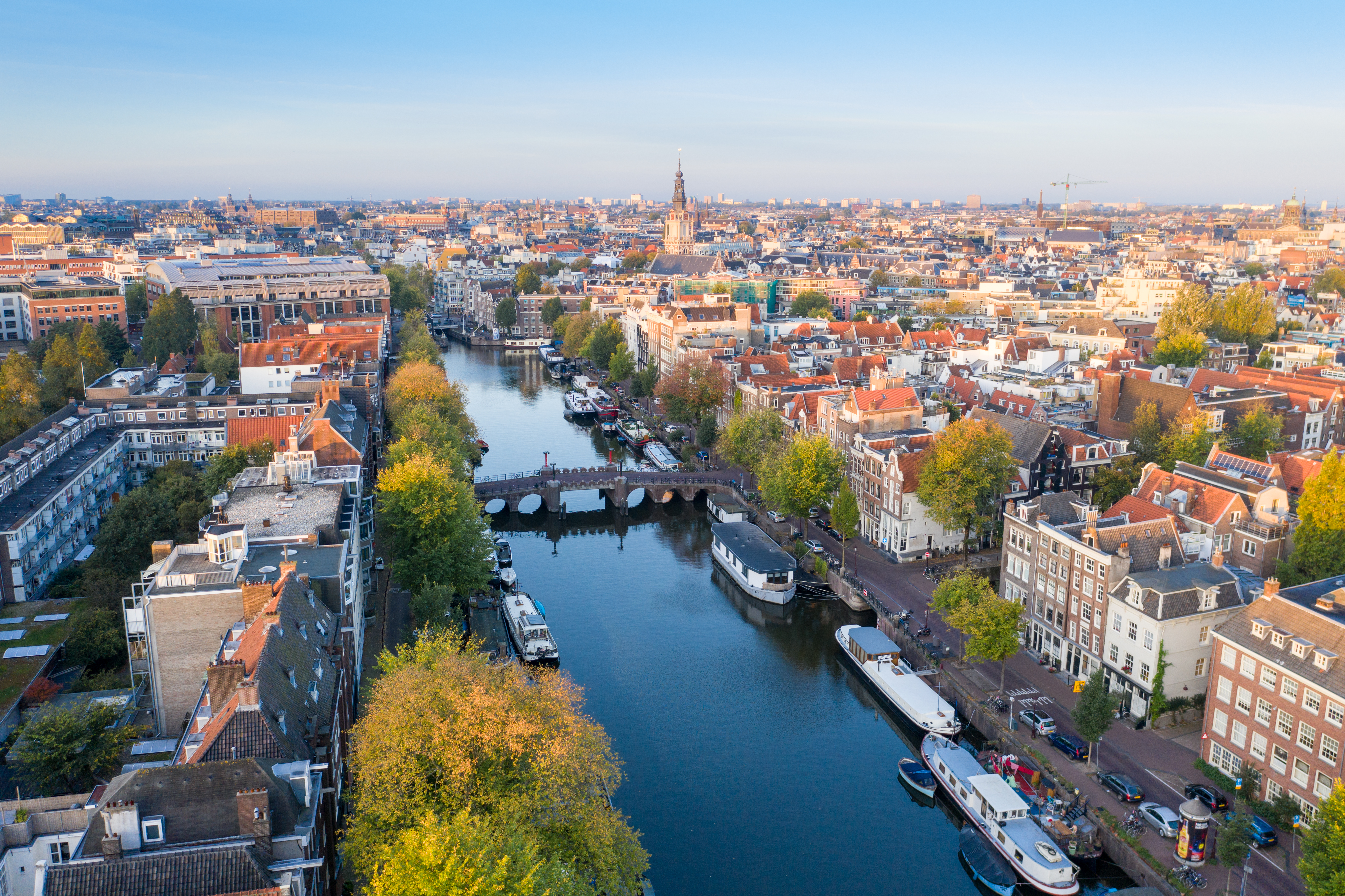 City aerial view over Amsterdam, The Netherlands. View from the bird's flight of narrow canals, streets and historical architecture.