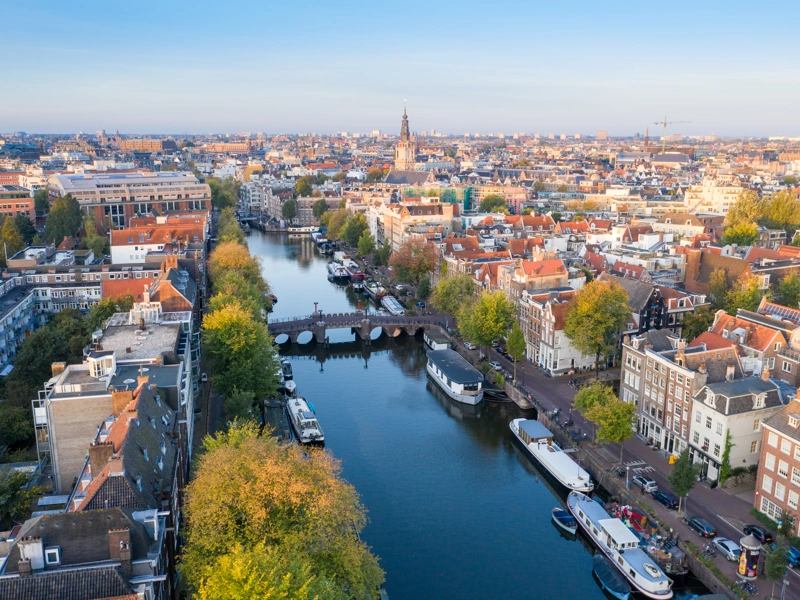 City aerial view over Amsterdam, The Netherlands. View from the bird's flight of narrow canals, streets and historical architecture.