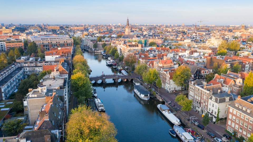 City aerial view over Amsterdam, The Netherlands. View from the bird's flight of narrow canals, streets and historical architecture.