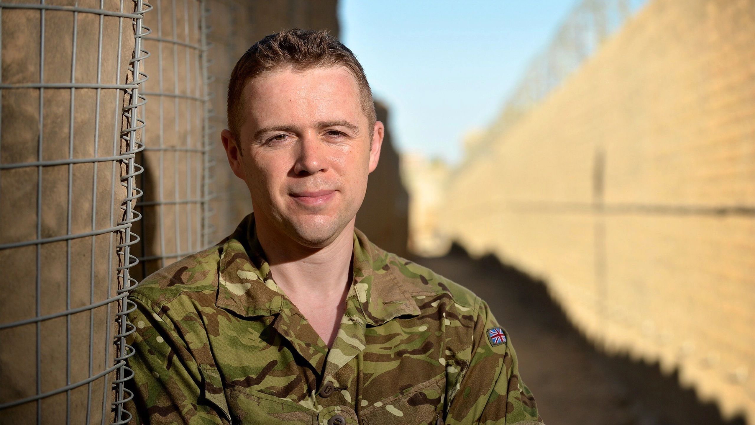 Portrait of a soldier smiling in uniform in a sandy landscape