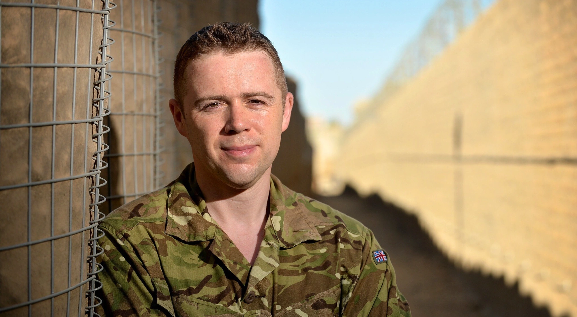 Portrait of a soldier smiling in uniform in a sandy landscape