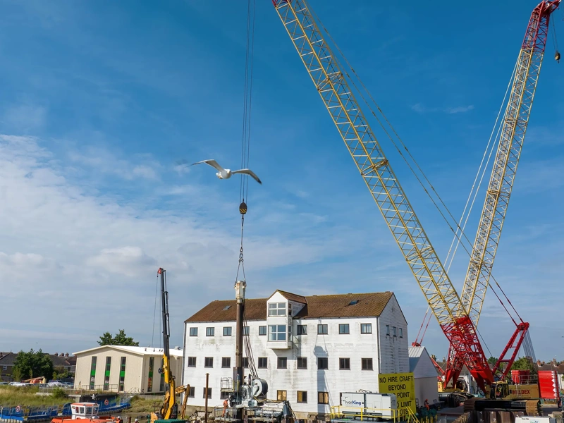 White house with blue sky with a crane in front of it.
