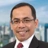 Portrait of Bayu Utomo, Director, Indonesia, outside in front of tall city buildings with blue skies.