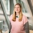 Portrait of Marissa Stenning inside office standing infront of windows in pink jumper