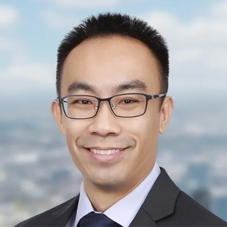 Portrait of Johnson Zi hao Chua, Head of Project Management, Singapore, outside in front of tall city buildings with blue skies.