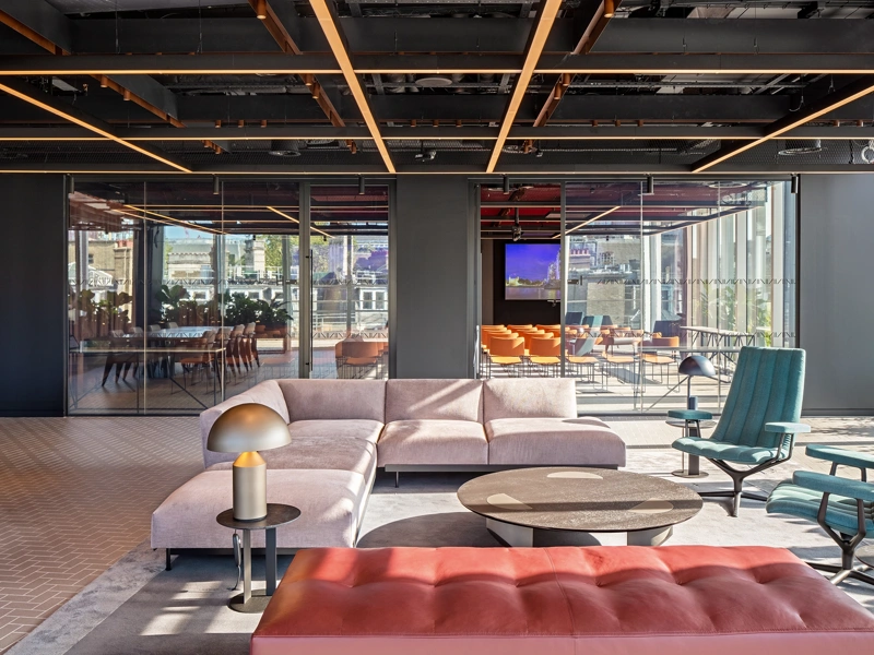 Modern, light-filled office interior with sofas in the foreground and a glass meeting room in the background