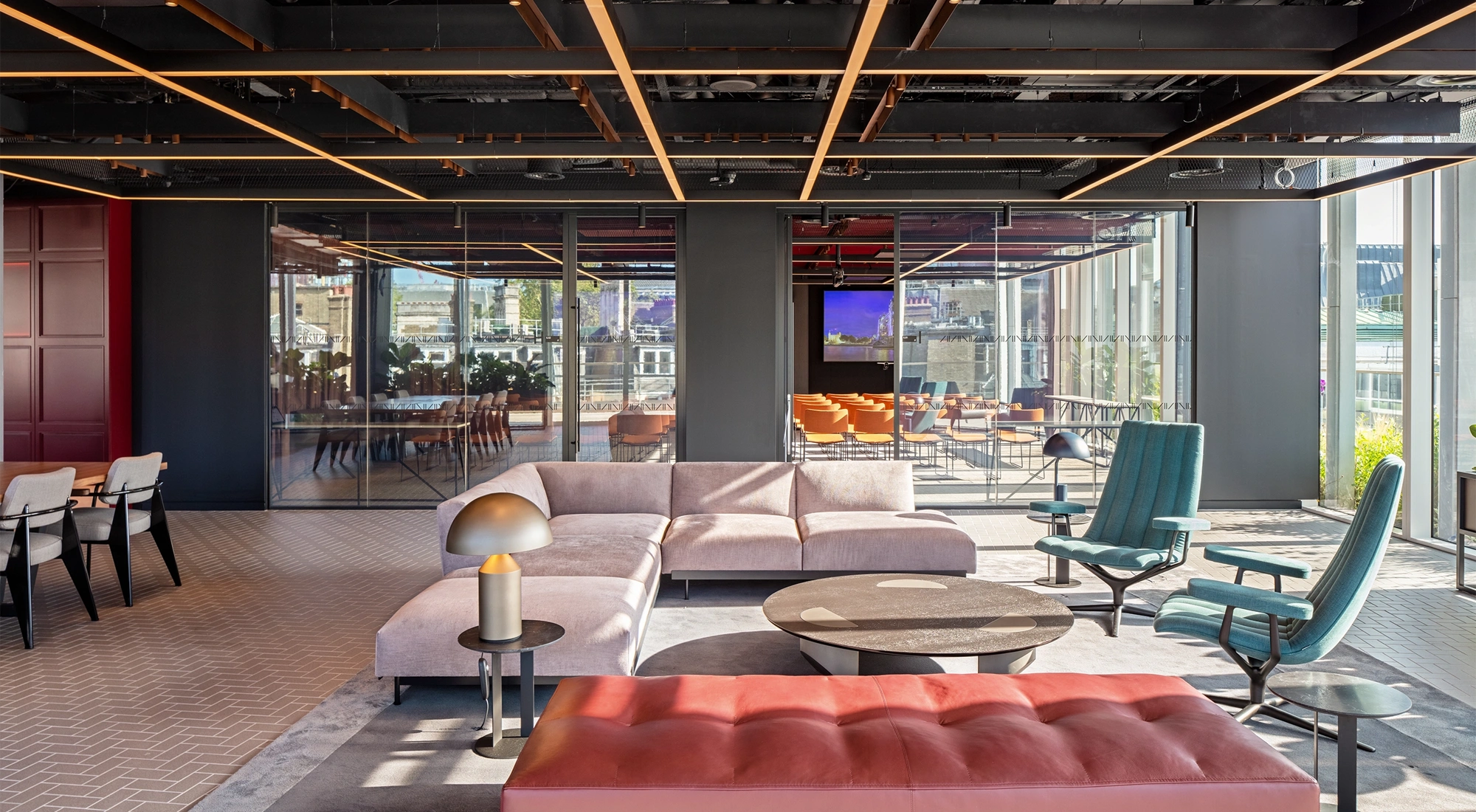 Modern, light-filled office interior with sofas in the foreground and a glass meeting room in the background
