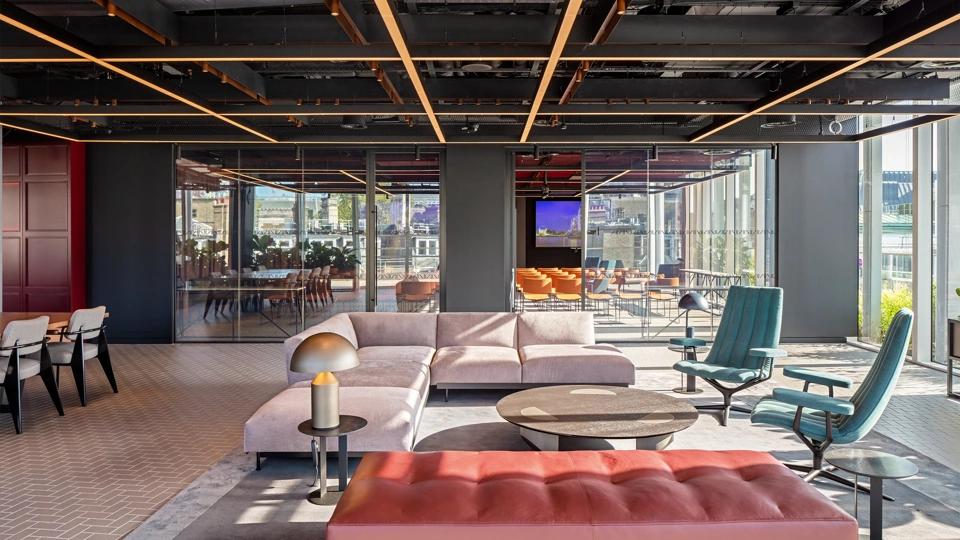 Modern, light-filled office interior with sofas in the foreground and a glass meeting room in the background