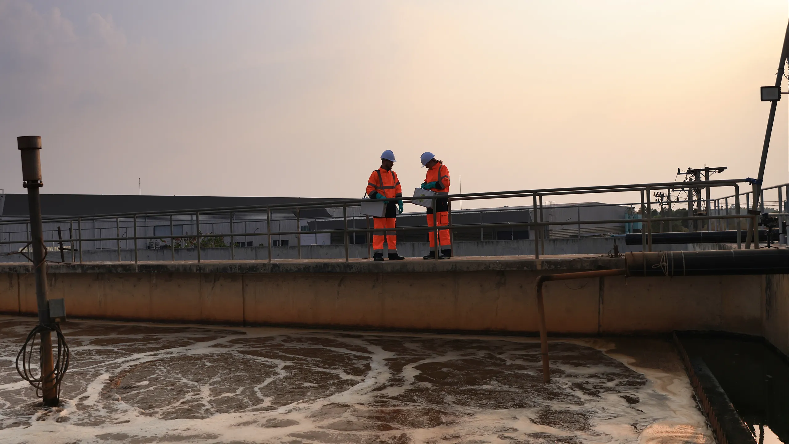 Safety and environmental engineers Working on the sunlight at a wastewater treatment plant in the industrial estate by walking around and checking the quality of the water
