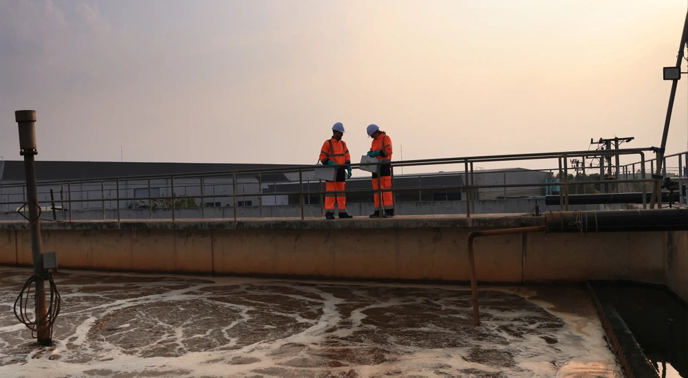 Safety and environmental engineers Working on the sunlight at a wastewater treatment plant in the industrial estate by walking around and checking the quality of the water