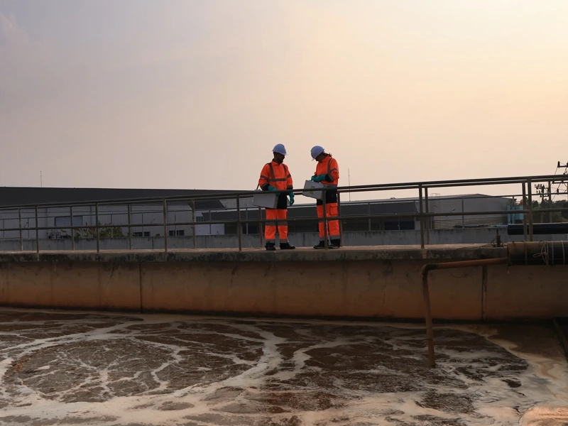 Safety and environmental engineers Working on the sunlight at a wastewater treatment plant in the industrial estate by walking around and checking the quality of the water