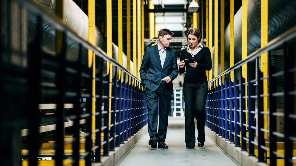 Two professionals walking through a factory