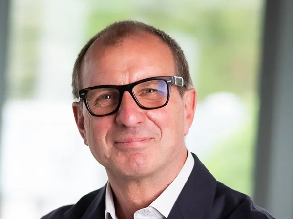 Steve Watts, Director, Real Estate, UK, in front of a window with trees behind him
