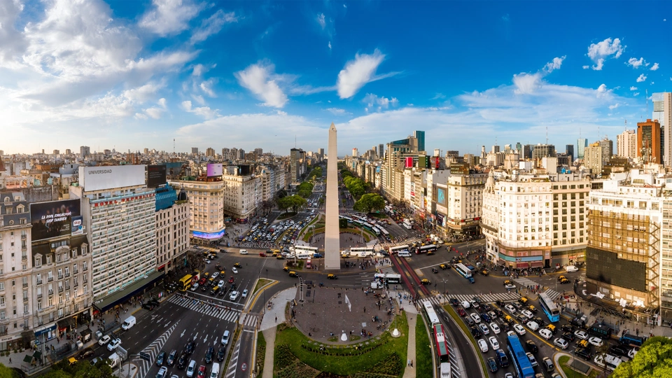Skyline view of Buenos Aires with lots of cars on the road and tall monument in the middle