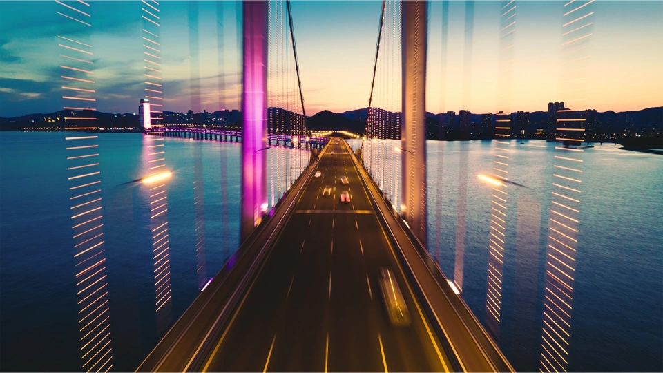 Road bridge over wide river at night with mountains in the background