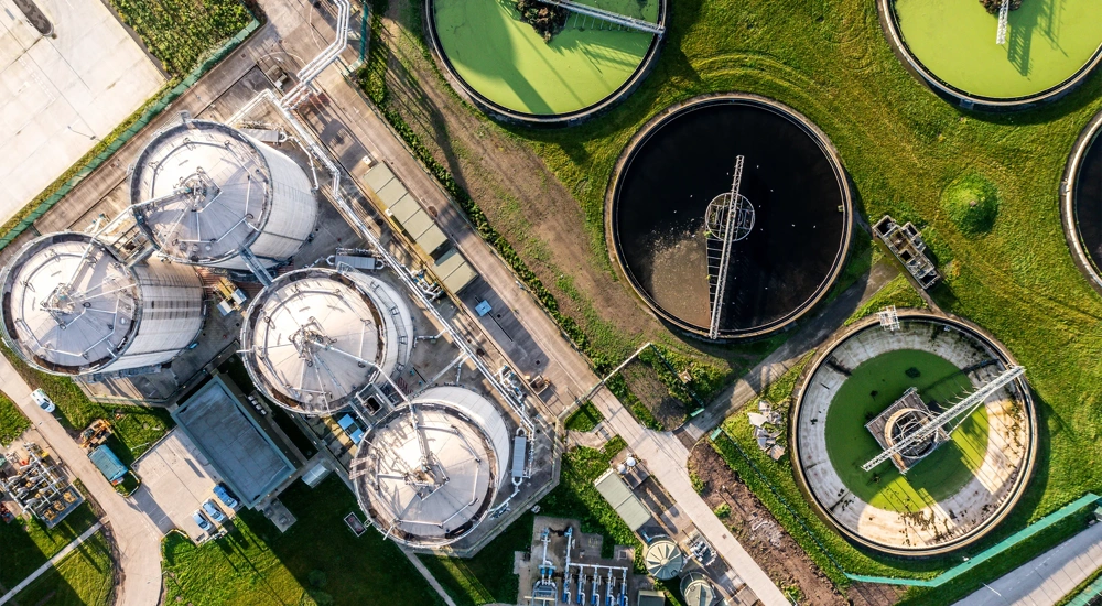 An aerial view directly above a waste water treatment works with circular storage tanks filtering wastewater for drinking water