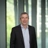 Rob Chomiak in modern office, with glass panels, and a softly blurred workspace behind.