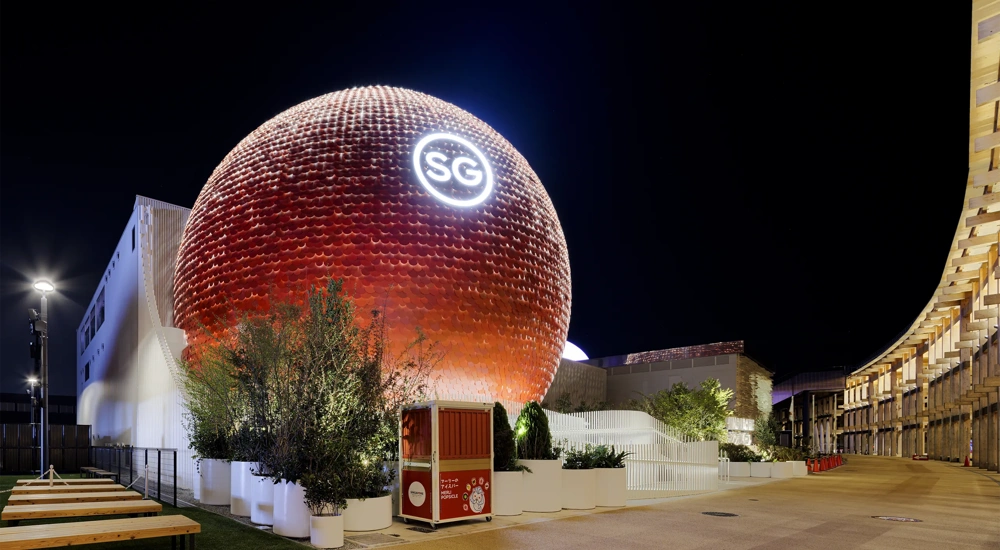 Night view of the Singapore Pavilion at Expo 2025 Osaka, Japan, featuring striking spherical red structure with the letters SG illuminated at the top.