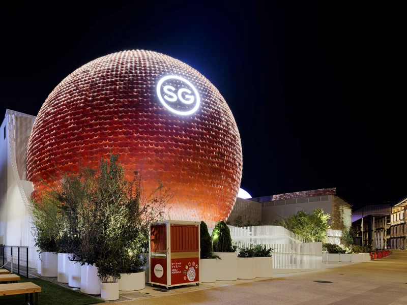 Night view of the Singapore Pavilion at Expo 2025 Osaka, Japan, featuring striking spherical red structure with the letters SG illuminated at the top.
