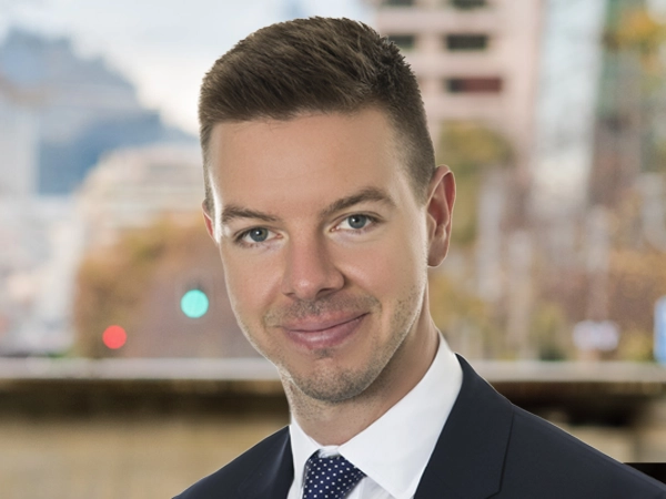 Portrait of Perry Knight, Vice President, standing outside featuring an urban cityscape with tall buildings and a mix of architectural styles. The scene includes some trees with autumn foliage, adding a touch of color.