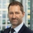 Portrait of Adam Ralph, Director, Dubai, with city landscape featuring building with lots of windows in the background.