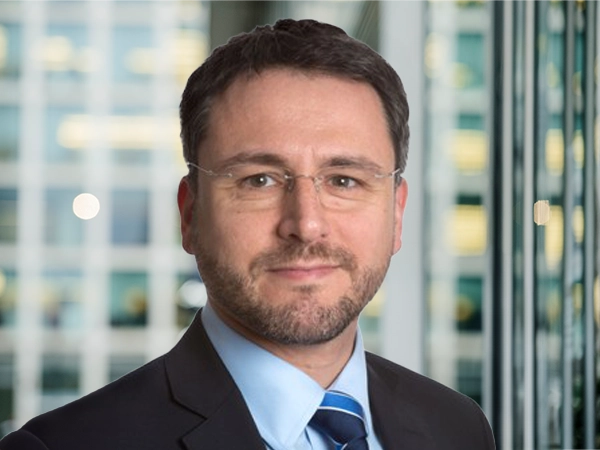 Portrait of Gaël Lehimas, Managing Director, France, with city landscape featuring building with lots of windows in the background.