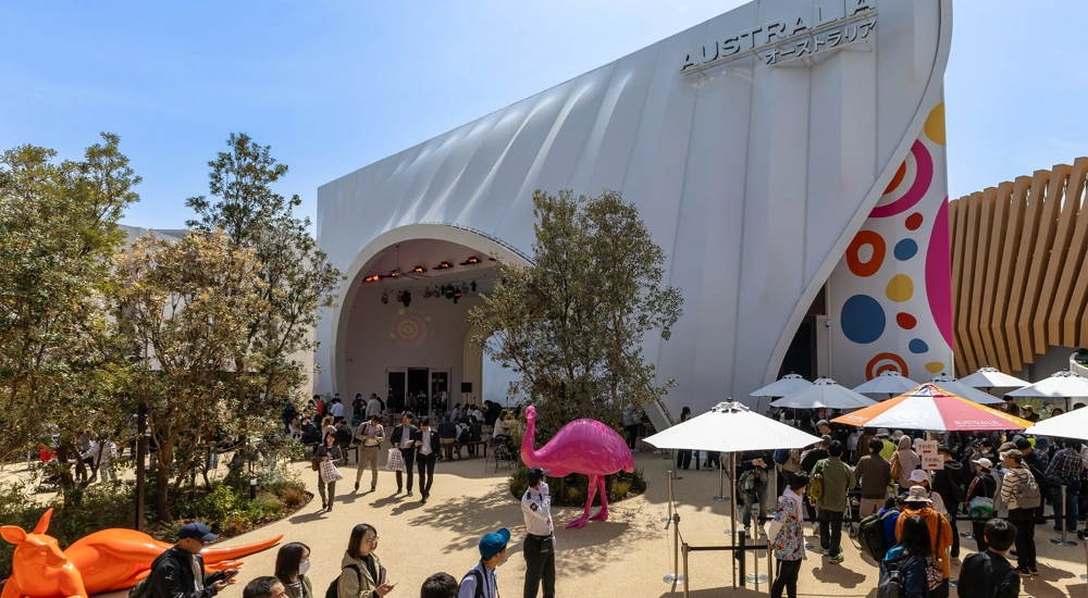 Australian and Japanese Expo at day time with blue skies and lots of visitors. There are colorful statue animals such as a orange kangaroo and pink flamingo.