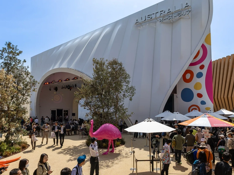Australian and Japanese Expo at day time with blue skies and lots of visitors. There are colorful statue animals such as a orange kangaroo and pink flamingo.