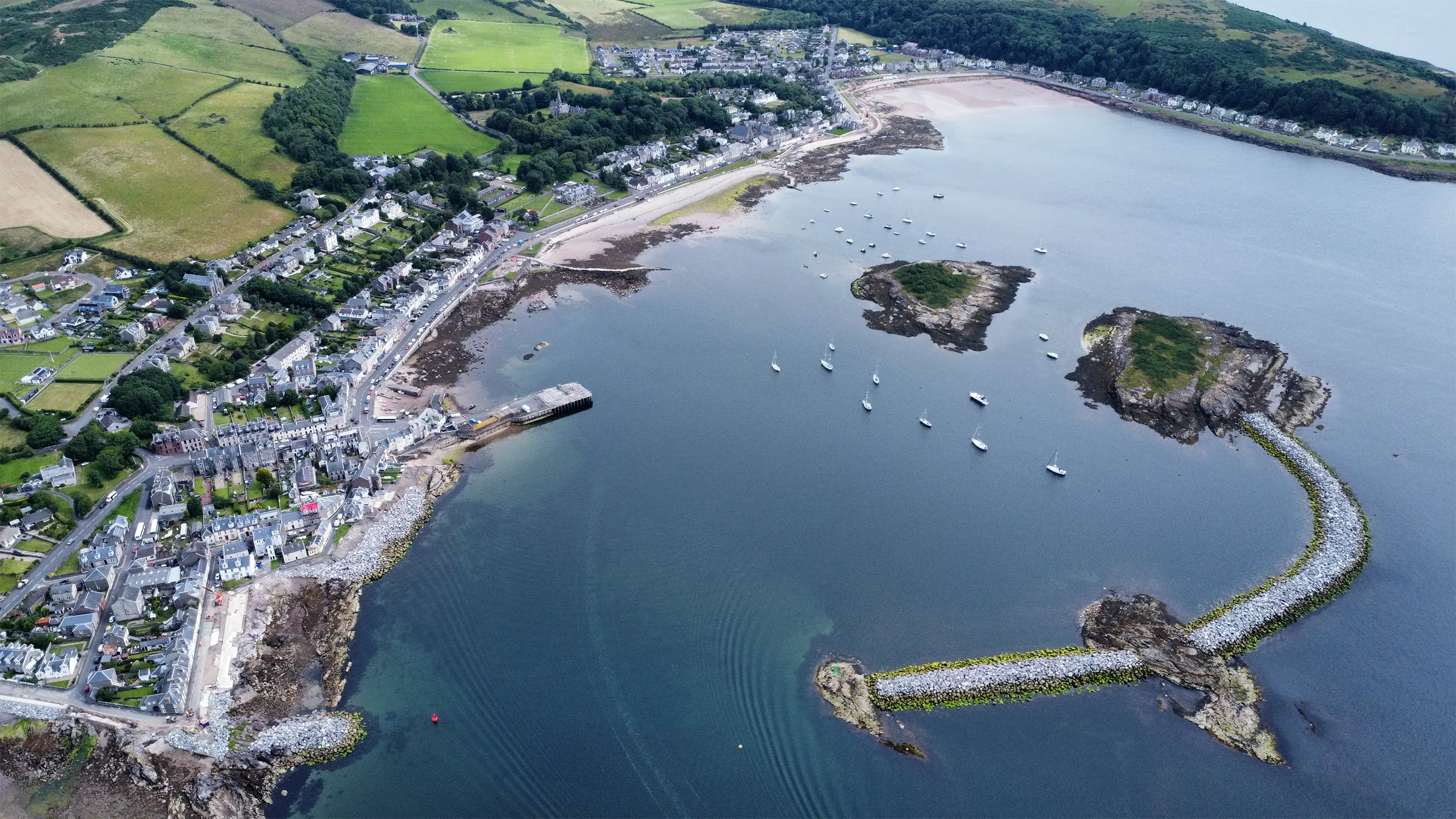 Areal view of harbor with green grass and blue sea