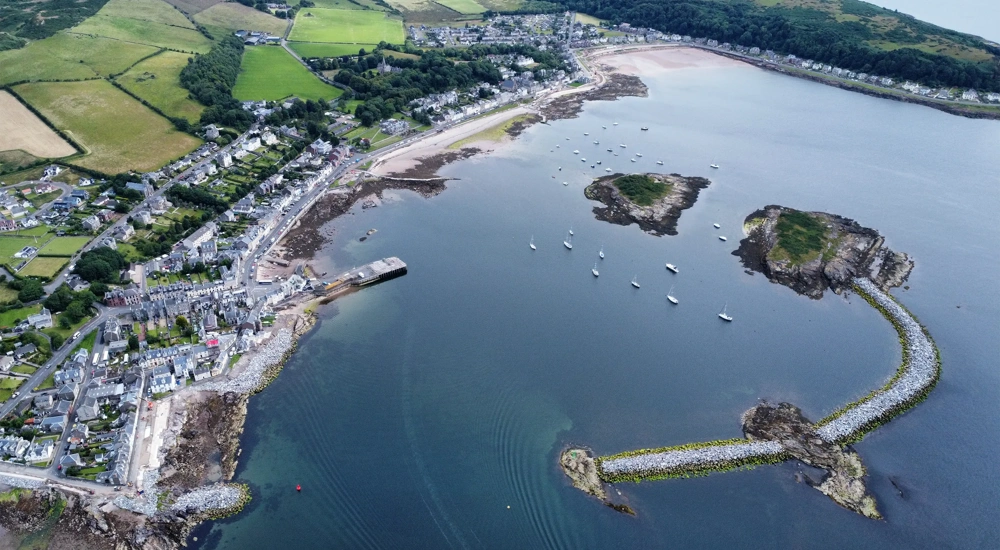 Areal view of harbor with green grass and blue sea