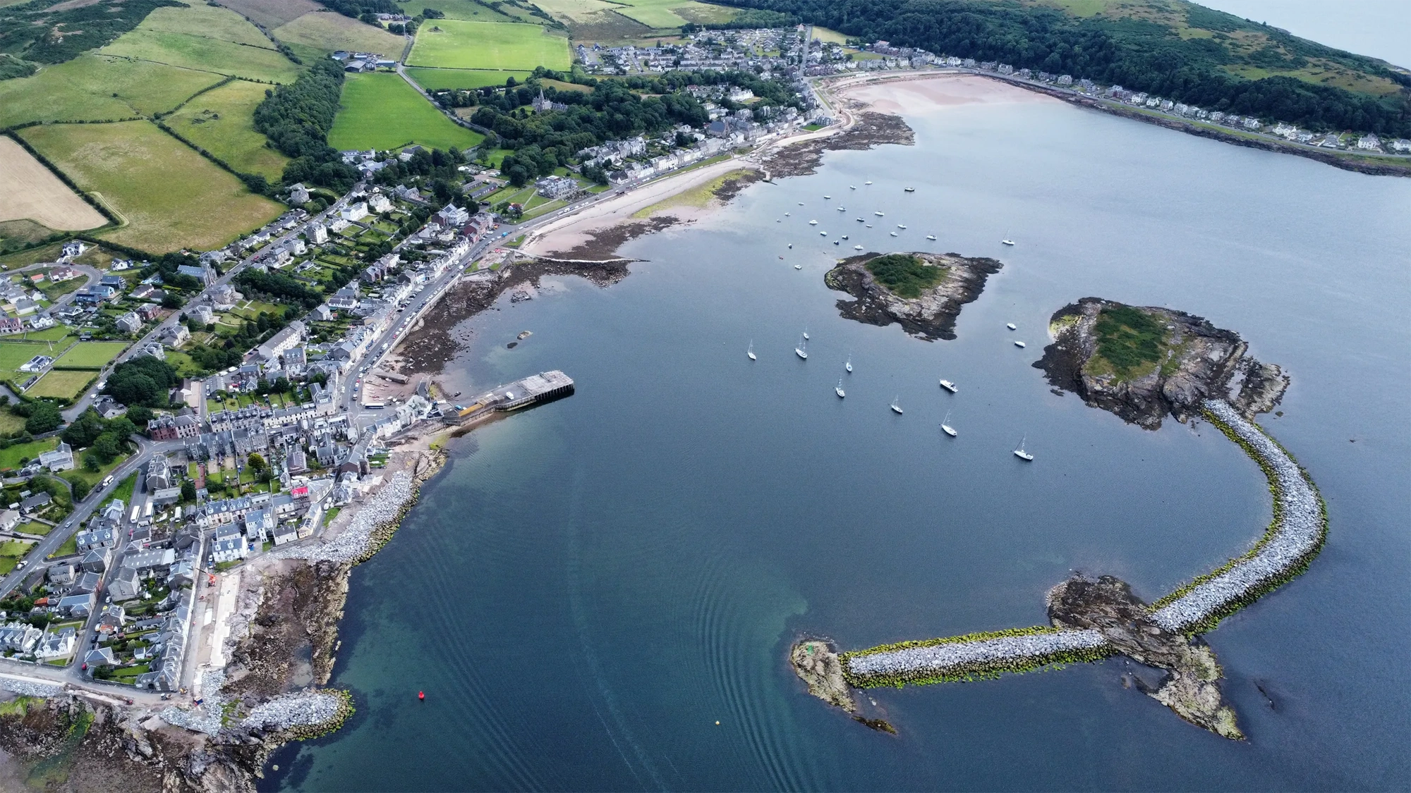Areal view of harbor with green grass and blue sea