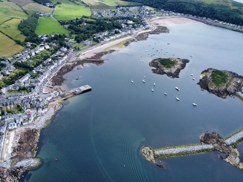 Areal view of harbor with green grass and blue sea