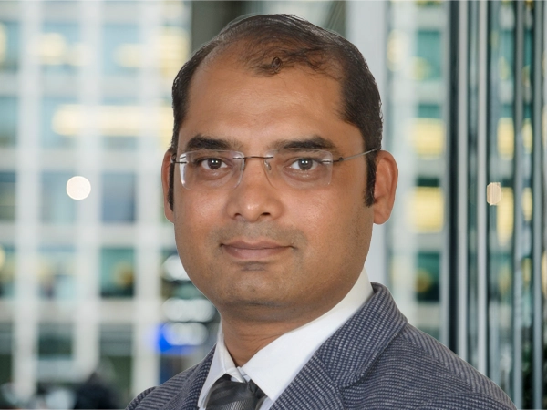 Portrait of Sarang D Molkar, Director, India, with city landscape featuring building with lots of windows in the background.