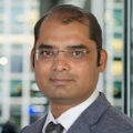 Portrait of Sarang D Molkar, Director, India, with city landscape featuring building with lots of windows in the background.