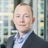 Portrait of Luke Pardoe, Project Director, standing in window based office building.