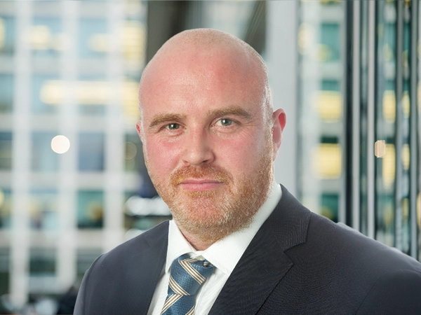 Portrait of Vincent Kane, Director, UK, Life Sciences, standing in window based office building.