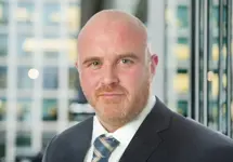 Portrait of Vincent Kane, Director, UK, Life Sciences, standing in window based office building.