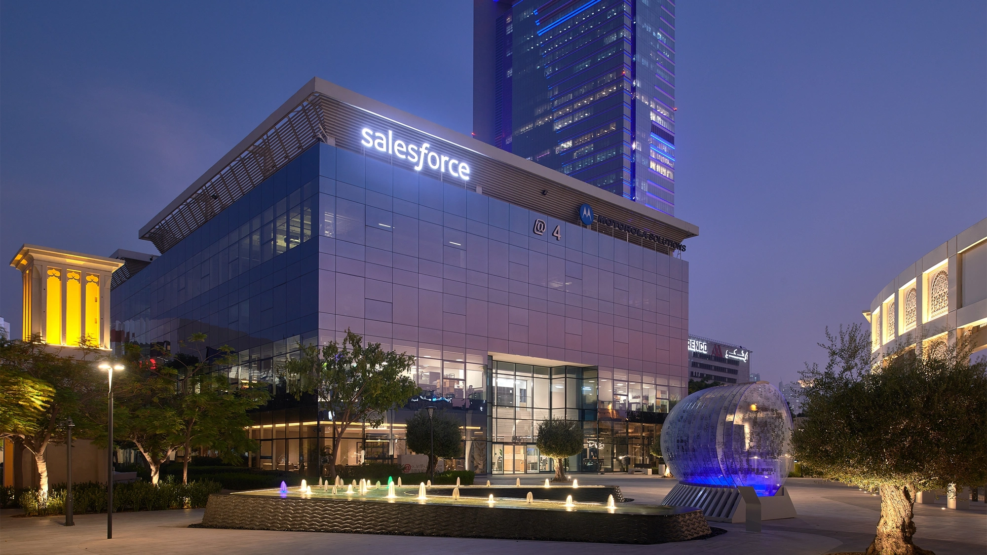 Image of Dubai Salesforce office at night, glass windows that reflects the purple ambiance of the night sky.