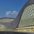 Curved glass building with yellow lights lit up inside