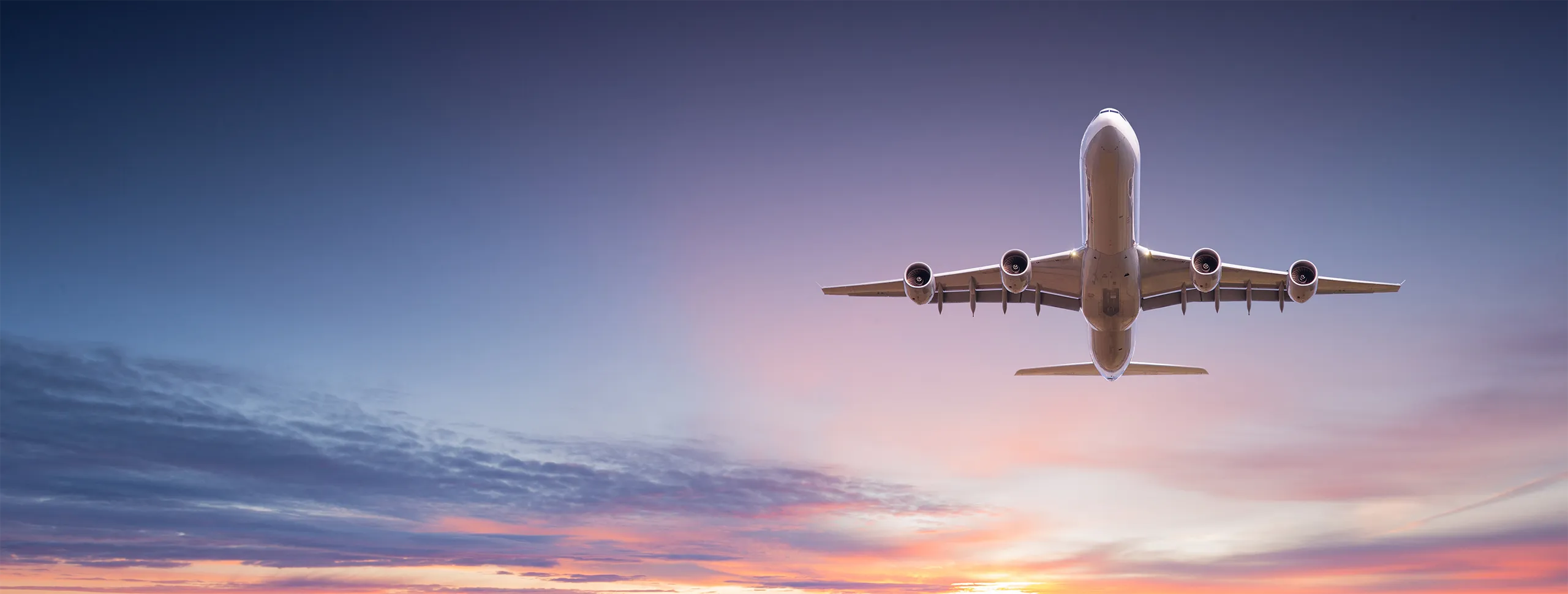 Commercial airplane jetliner flying above dramatic clouds in beautiful sunset light. Travel concept.
