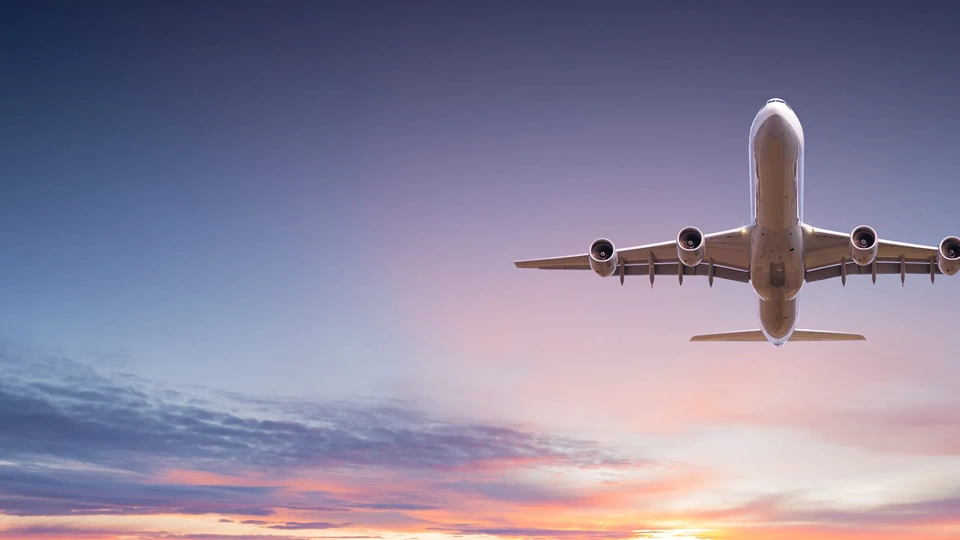 Commercial airplane jetliner flying above dramatic clouds in beautiful sunset light. Travel concept.