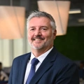 Portrait of Kobus Havemann, Country Manager, Smiling in blue suit in blue themed office space.
