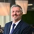 Portrait of Kobus Havemann, Country Manager, Smiling in blue suit in blue themed office space.