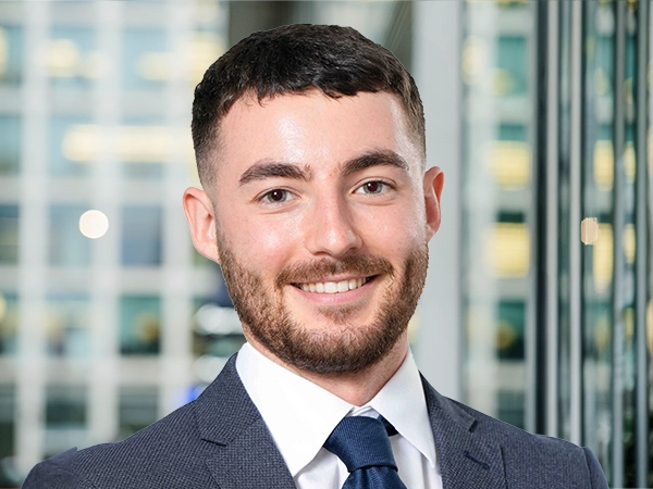 Portrait of Calum Watson, Project Manager, with city landscape featuring building with lots of windows in the background.