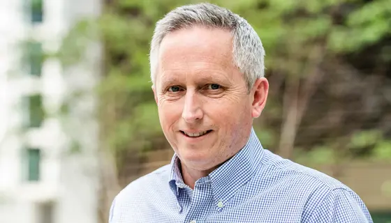 Martin Sudweeks, UK Managing Director, Cost and Commercial Management, smiling in a blue shirt outside in front of trees