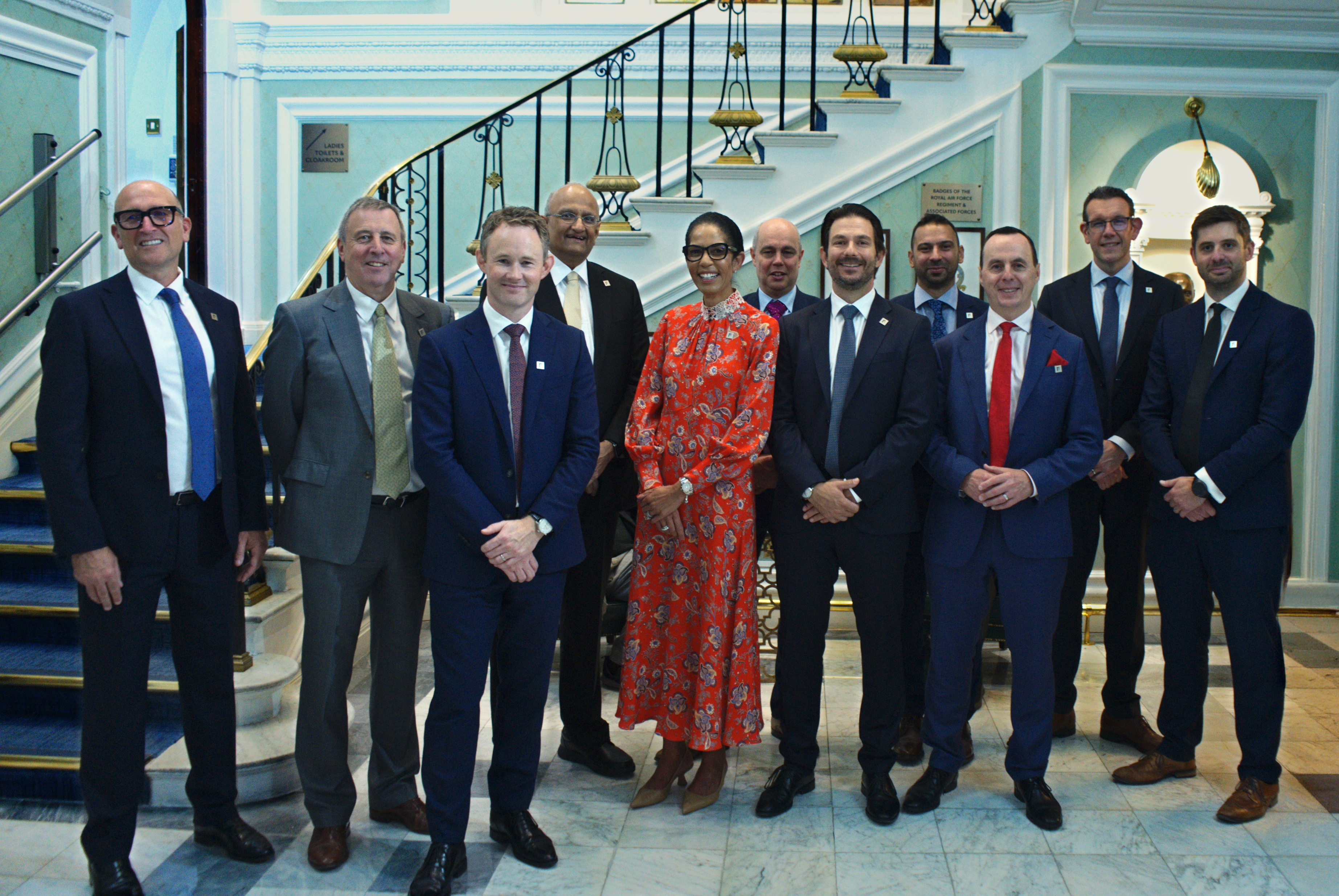 Group of Turner & Townsend professionals standing smiling for a picture in suits.