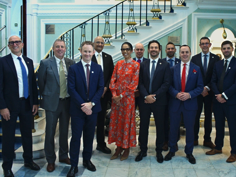 Group of Turner & Townsend professionals standing smiling for a picture in suits.